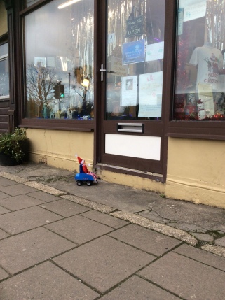 Toy Elf in powered wheelchair unable to get up a step into a gift shop.